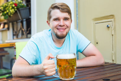 Portrait of smiling man drinking glass on table
