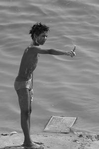 Semi-naked boy gesturing while standing on lakeshore