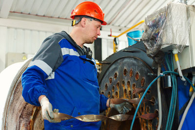 Engineer in helmet inspects and repairs gas equipment of boiler room. cleaning and maintenance of