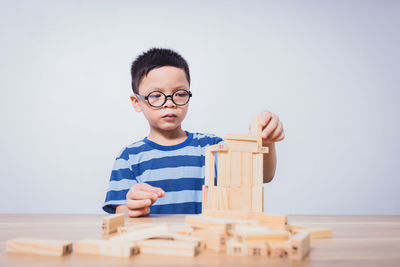 Portrait of boy playing with toy blocks on table against white background