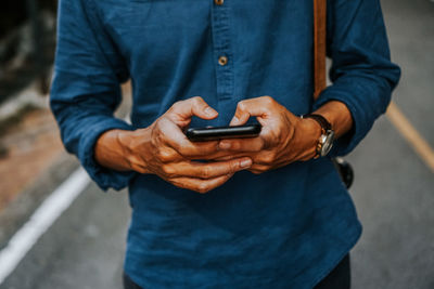 Midsection of man using mobile phone