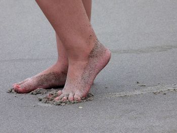 Low section on person standing at sandy beach