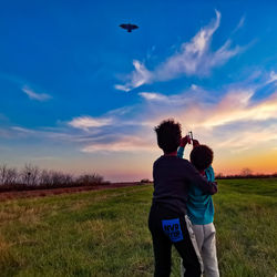 Rear view of man and woman on field against sky