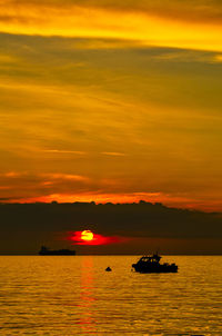 Silhouette boat in sea against sky during sunset