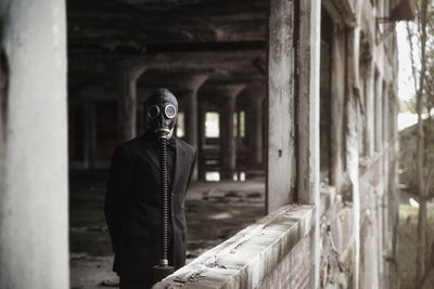 Man wearing gas mask standing in abandoned building