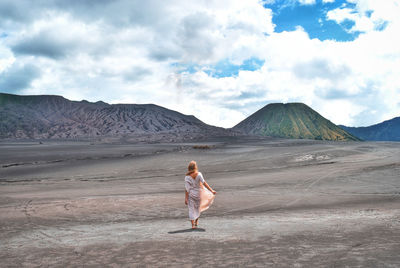 Rear view of man standing on land against sky