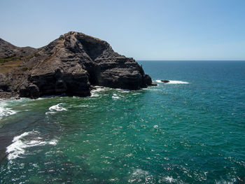 Scenic view of rocks in sea against clear sky