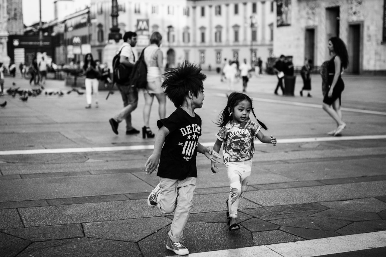 street, walking, person, city, city life, lifestyles, men, large group of people, building exterior, leisure activity, full length, rear view, city street, architecture, built structure, casual clothing, sidewalk, road, on the move