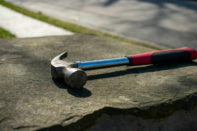 A hammer with a red and black handle on a cobblestone pillar on a suburban street