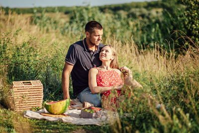 Young couple in love on summer picnic with watermelon. loving couple sitting by the river, talking