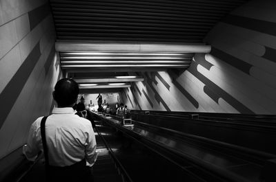 Rear view of man standing on escalator