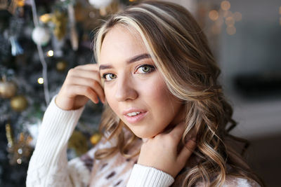 Happy cute girl in a cozy sweater celebrates christmas prepares gift boxes at home indoor