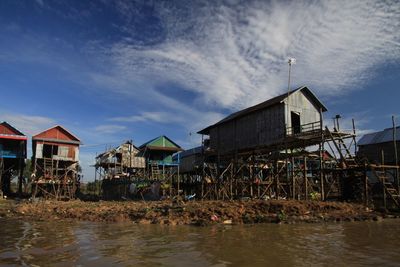 Buildings by river against sky