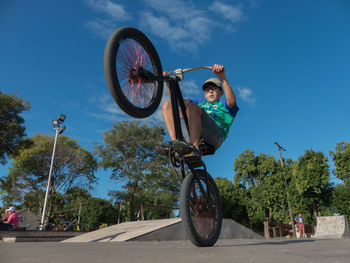 Low angle view of man riding bicycle against sky