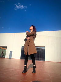 Side view of woman standing on floor against sky