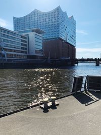 Modern building by river against sky in city