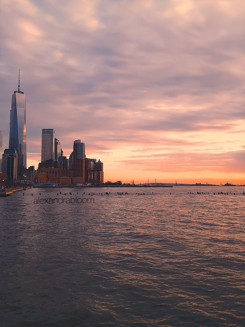 water, sunset, building exterior, sky, waterfront, architecture, built structure, cloud - sky, sea, rippled, river, orange color, city, cloud, cloudy, scenics, nature, beauty in nature, reflection, tranquility