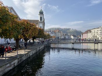 People on river by buildings in city