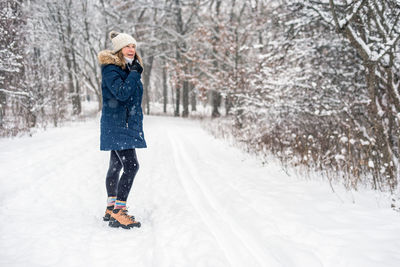 Woman standing in snow covered tree