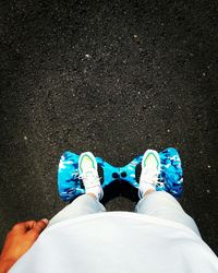 Low section of man standing on hoverboard at road