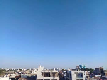 Buildings in city against clear blue sky