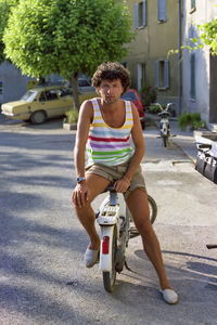 View of a young man sitting on a scooter in the street