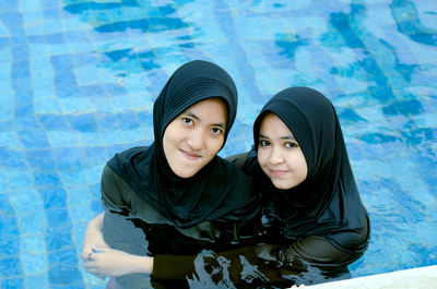 Portrait of young woman standing against swimming pool