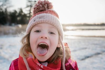 Young girl catching snow on her tongue outside in winter