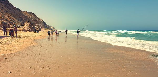 People on beach against clear sky