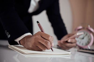 Midsection of woman holding paper at table