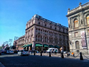 View of city street and buildings against blue sky