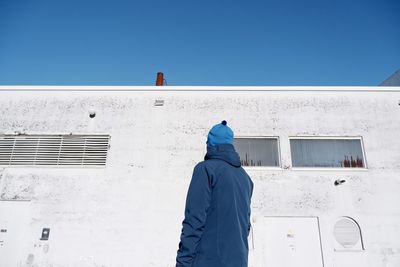 Rear view of man standing against blue sky