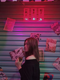 Woman standing against pink wall