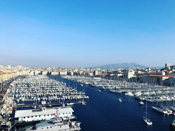 High angle view of harbor by buildings against clear blue sky