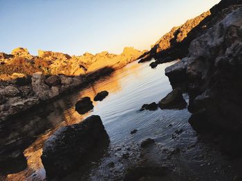 Rock formation on sea against sky during sunset