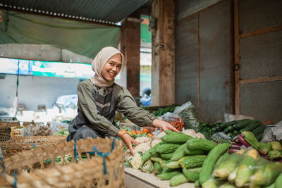 Portrait of young woman holding vegetables for sale at market