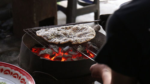 Midsection of person preparing food on barbecue grill