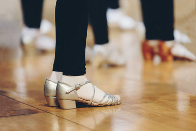 Low section of woman wearing sandals standing on hardwood floor