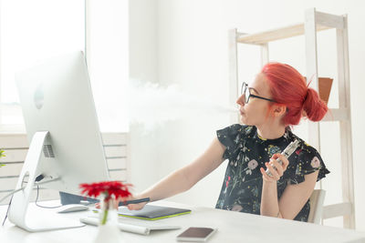 Young woman using mobile phone while sitting on table