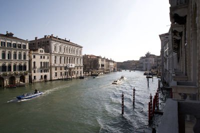 Canal amidst buildings in city against clear sky