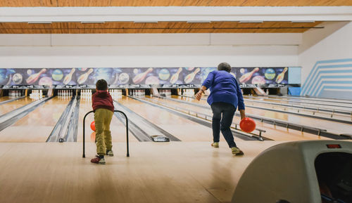 Older woman and young child bowling together at bowling alley.
