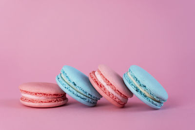 Delicious colorful french cookies macaroons on pink background. copy space.