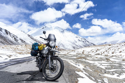 Man riding motorcycle on snowcapped mountain against sky