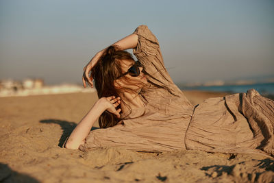 Rear view of woman sitting on sand at beach