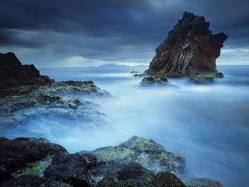 Rock formations in sea against cloudy sky at madeira