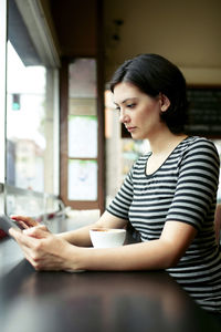 Young woman using tablet computer at cafe table