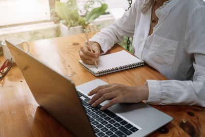 Midsection of man using laptop on table