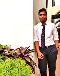 Portrait of young man standing against wall