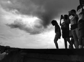 Low angle view of people standing against sky