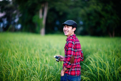 Portrait of smiling young man standing on field